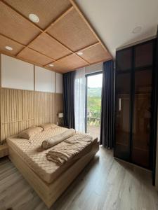 a bedroom with a large bed and a large window at Ogimi Villas Bảo Lộc in Blao Srê