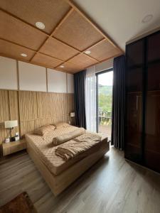 a bedroom with a large bed and a large window at Ogimi Villas Bảo Lộc in Blao Srê