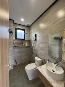 a bathroom with a toilet and a sink at Ogimi Villas Bảo Lộc in Blao Srê