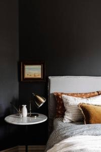 1 dormitorio con 1 cama y 1 mesa con lámpara en Sailors Whisk, luxurious restored antique cottage en Flinders