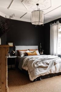 1 dormitorio con cama y pared negra en Sailors Whisk, luxurious restored antique cottage en Flinders