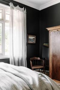 1 dormitorio con cama, ventana y silla en Sailors Whisk, luxurious restored antique cottage en Flinders