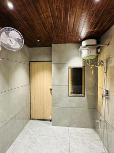 baño con ducha y puerta de madera en MG apartments en Jodhpur