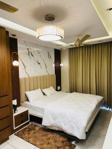 una camera da letto con un grande letto bianco e un lampadario a braccio di MG apartments a Jodhpur