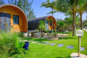 uma casa com um jardim de relva com uma árvore em KIGI Beach Resort em Phan Thiet