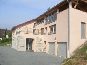un grand bâtiment en briques avec deux portes de garage dans l'établissement Gîte La Rosa, à Ornans