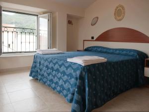 a bedroom with a bed with a blue comforter and a window at Residence Pax in Fiumaretta di Ameglia