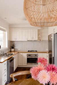 a kitchen with white cabinets and a chandelier at Banksia Beach House in Port Fairy