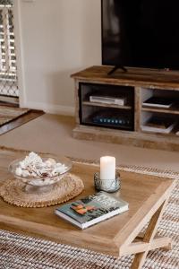 a living room with a table with a candle and a television at Banksia Beach House in Port Fairy