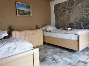 a bedroom with two beds and a stone wall at Ferienhaus Emilia in Wilthen