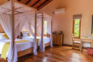 a bedroom with two beds and a canopy bed at Sigiriya Forest Edge By Marino Leisure in Sigiriya