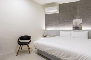una camera con un letto bianco e una sedia nera di 礁溪亞都溫泉旅店 Newly Renovated a Jiaoxi