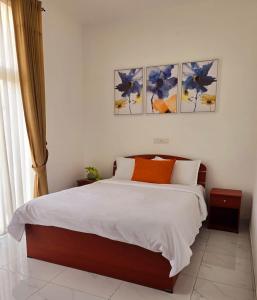 een slaapkamer met een bed en drie schilderijen aan de muur bij Meadows Living 2 BR Apartment near Mount Beach in Karagampitiya