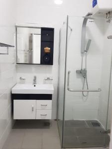 een badkamer met een wastafel en een douche met een spiegel bij Meadows Living 2 BR Apartment near Mount Beach in Karagampitiya