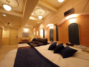 a bedroom with a large bed and a living room at ホテル カーシュ Cache 男塾ホテルグループ in Himeji