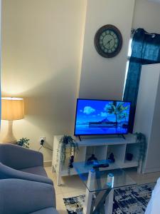 a living room with a tv and a clock on the wall at Studio Appartment in Building in Ras al Khaimah