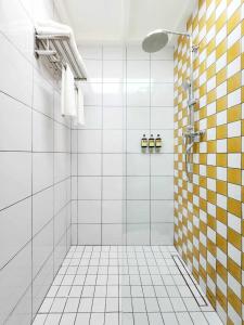 Łazienka z prysznicem wyłożona jest żółtymi i białymi kafelkami. w obiekcie Senglao Boutique Hotel Luang Prabang w mieście Luang Prabang