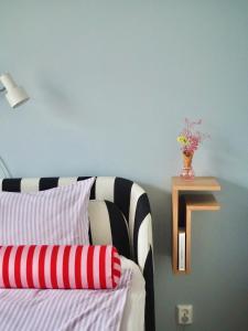 um quarto com uma cama e um vaso de flores numa prateleira em Candy-Colored Two-Room Condo with Sweet views em Helsínquia
