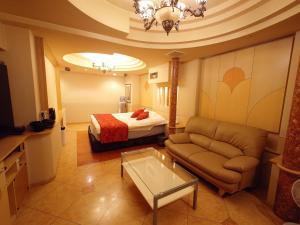 une chambre d'hôtel avec un lit, un canapé et une table dans l'établissement ホテル カーシュ Cache 男塾ホテルグループ, à Himeji