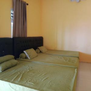 2 camas individuales en una habitación con ventana en Karang Besi Losmen en Biha
