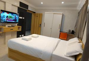 una camera da letto con un letto grande e una TV a schermo piatto di Arasan Residency a Kotagiri