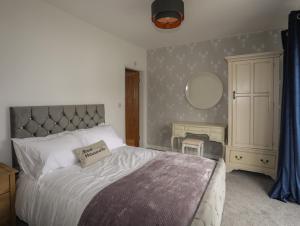 a bedroom with a bed and a dresser and a mirror at Blue Bay Villa in Holyhead