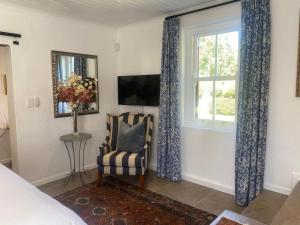 1 dormitorio con ventana, silla y TV en La Terrazza, en Riebeek-Wes