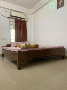 a large wooden bed in a room with a window at Sandhya Guest House in Digha