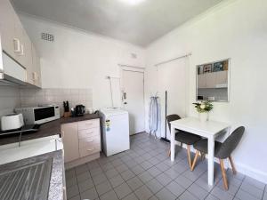 雪梨的住宿－Budget 1 bedroom unit near Maroubra Beach，厨房配有桌子和白色冰箱。