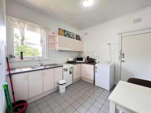 a kitchen with white cabinets and a sink and refrigerator at Budget 1 bedroom unit near Maroubra Beach in Sydney