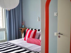 um quarto com uma cama com almofadas vermelhas e brancas em Candy-Colored Two-Room Condo with Sweet views em Helsinque