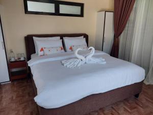 due cigni bianchi seduti sopra un letto di MaClare Resort a Imus