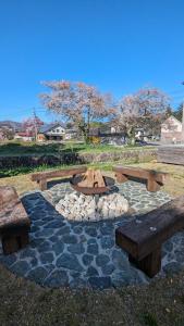 a park with benches and a fire pit in the grass at JOKIJOKI Hakuba in Hakuba