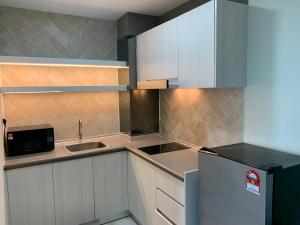 a kitchen with white cabinets and a sink and a refrigerator at Jesselton QUAY PICKNSTAY 拾旅 near gaya street near jesslton point near suria sabah in Kota Kinabalu