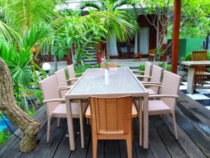 a table and chairs on a patio with palm trees at Lembongan Cempaka Villa & Restaurant in Nusa Lembongan