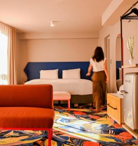 une femme traversant une chambre avec un lit dans l'établissement Adge Hotel and Residence - Adge King - Australia, à Sydney