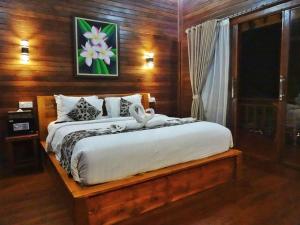 una camera da letto con un letto con un dipinto a fiori sul muro di Villa Cempaka Lembongan a Nusa Lembongan