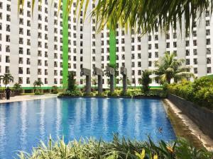 a large building with a large swimming pool in front of it at Pelangi Rooms By Reccoma in Pondokcabe Hilir