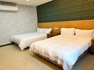 um quarto com duas camas e uma parede verde em Mucha Boutique Hotel em Yilan City