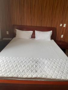 uma cama grande com lençóis brancos e almofadas em Trúc Lâm hotel em Hải Dương