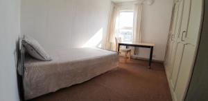 1 dormitorio con cama, escritorio y ventana en Homestay CR7, en Thornton Heath