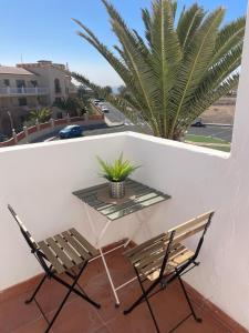 two chairs and a table on a balcony with a palm tree at Casa Del Mar in Costa de Antigua