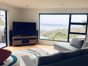 Una sala de estar con un sofá y un televisor de pantalla plana. en Modern executive house, stunning views over Hobart, en Sandy Bay