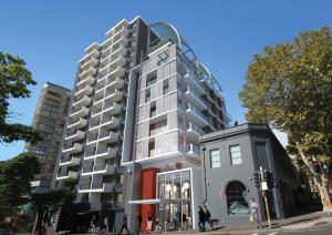 un edificio de apartamentos alto con una montaña rusa en la parte superior en Adge Hotel and Residence - Adge King - Australia en Sídney