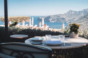 a table with plates and glasses and a view of the ocean at Sa Pedrissa in Deia