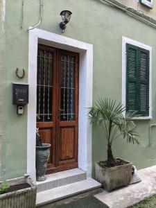 a green building with a wooden door and a potted plant at lake dreams in Verbania