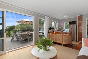 uma sala de estar em plano aberto com uma cozinha e um deque em Kereru Cottage - Matapouri Holiday Home em Whangarei