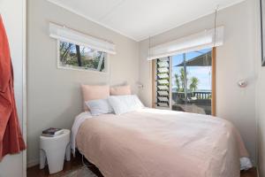Habitación blanca con cama y ventana en Kereru Cottage - Matapouri Holiday Home en Whangarei