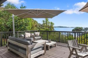 un patio con 2 sillas y una sombrilla en Kereru Cottage - Matapouri Holiday Home en Whangarei