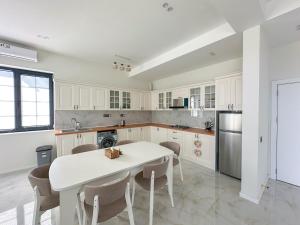 a white kitchen with a white table and chairs at White Harmony House in Şamaxı